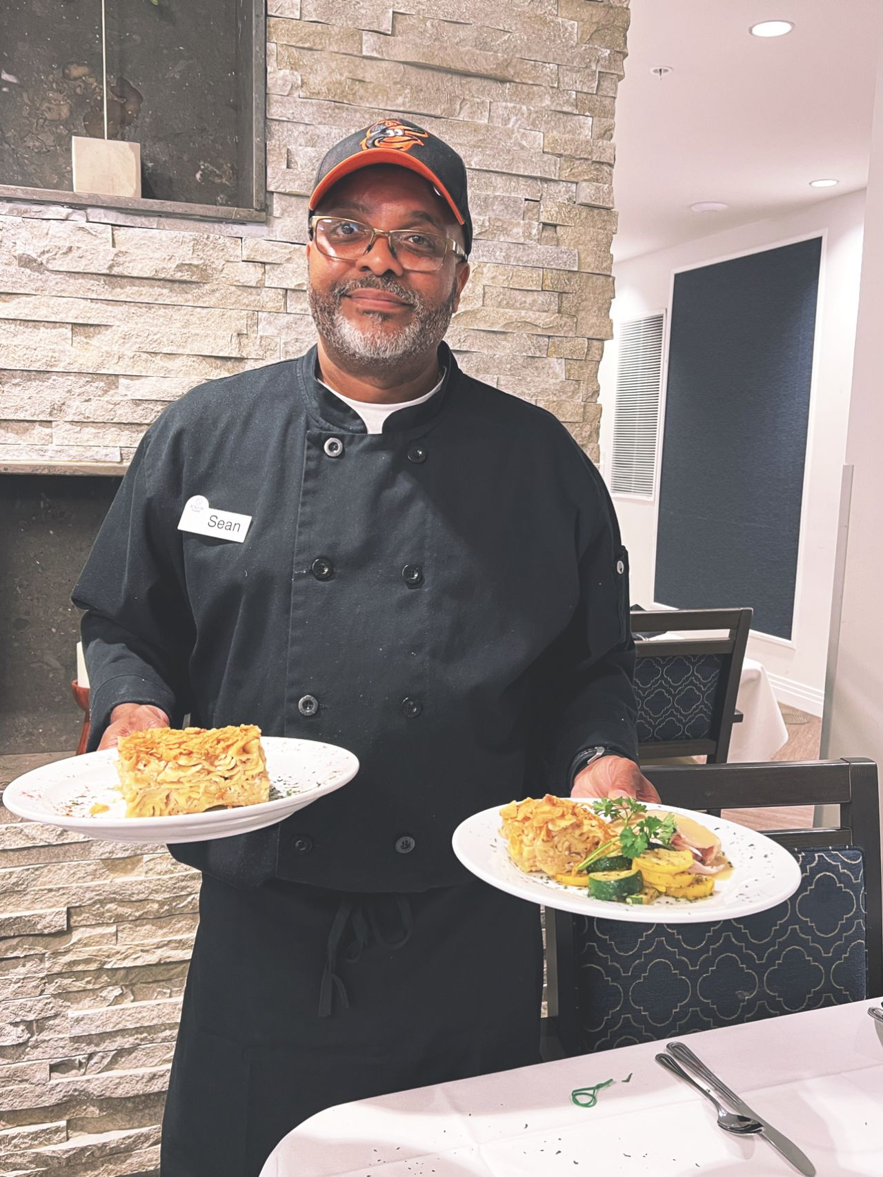 Atrium Village Chef Sean holding two beautiful plates of gourmet food