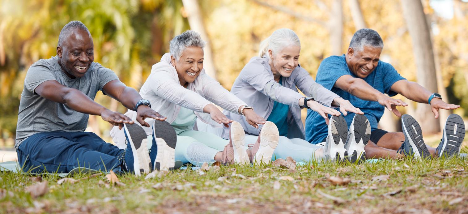 four seniors smiling while stretching outside